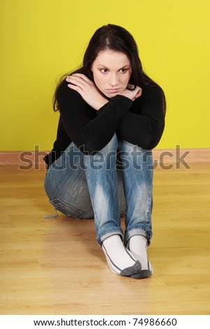A worried and afraid young woman sitting on the floor.