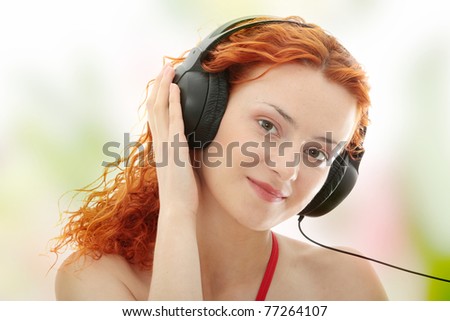 Attractive smiling redhead woman with headphones listening music