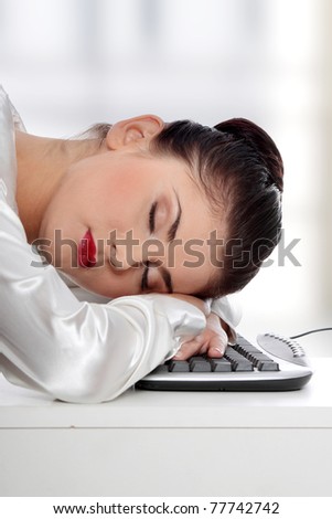 Young businesswoman sleeping on the keyboard in the office.