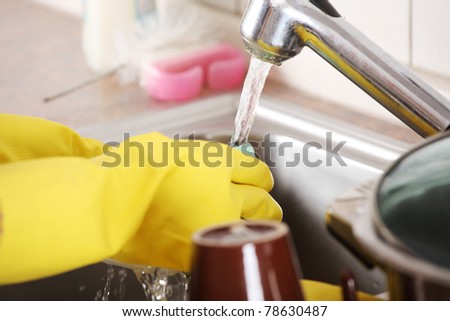 Hands in yellow glows washing dish