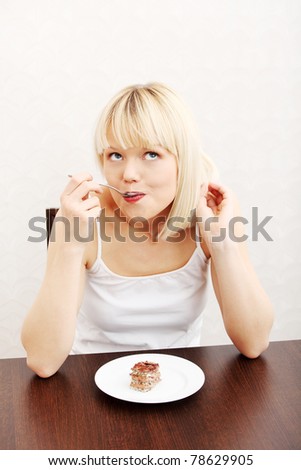 Beautiful woman eating cake. In home.
