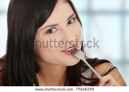 Portrait of young smiling woman with fork in her mouth and (pleasure from eating)