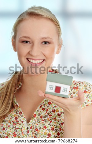 Close up photo of happy young woman holding house model
