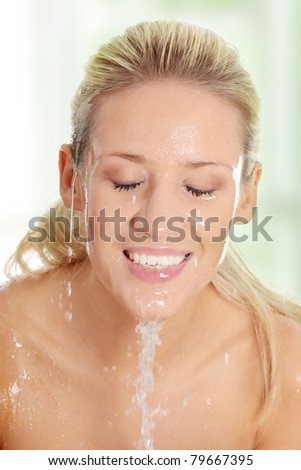 Young beautiful blond female washing her face with clear water