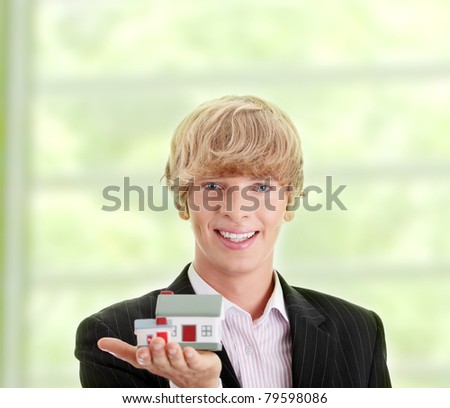 Young handsome business man with house model - real estate