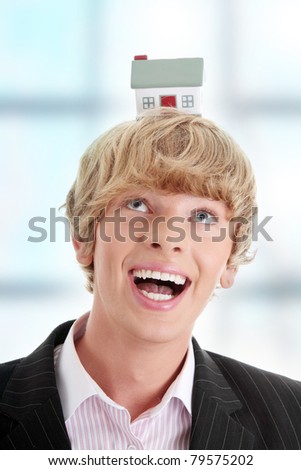 Young handsome business man with house model on head- real estate