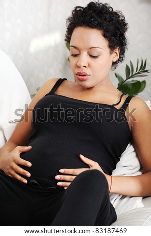 stock photo Young pregnant woman sitting on sofa