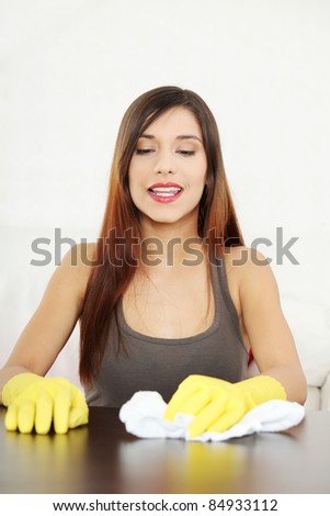 Young woman cleaning furniture table in yellow gloves