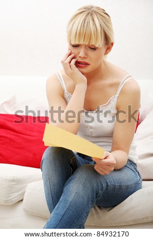 Worried woman's reading letter, at home.