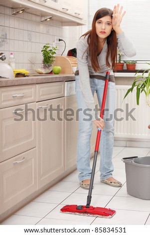 Woman holding a mop and cleaning kitchen floor