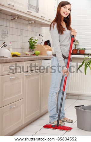 Woman holding a mop and cleaning kitchen floor