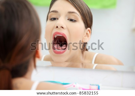 Young beautiful caucasian woman stands about a mirror in a bathroom  with open mouth
