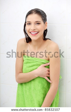 Beautiful woman wipes her wet body with a towel at bathroom