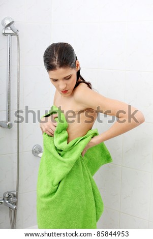 Beautiful woman wipes her wet body with a towel at bathroom