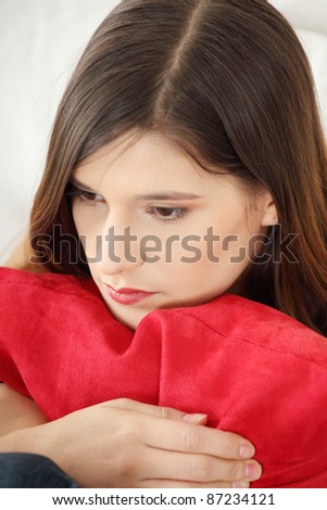 Sad woman\'s sitting on couch and squeezing pillow.
