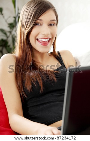 Young woman\'s working on laptop and smiling to camera. In home.