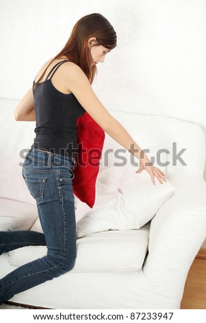 Young woman searching something under pillow of sofa