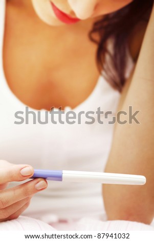Smiling woman holding a pregnancy test.