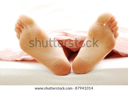 Beautiful feet of a young woman lying in bed, closeup
