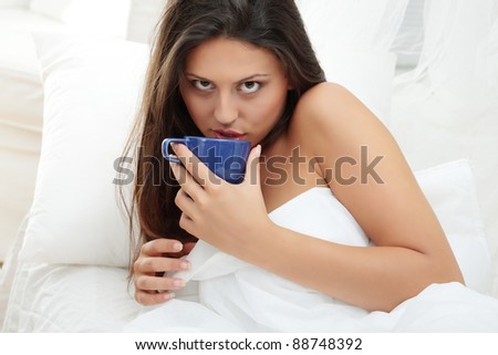 Beautiful lady is drinking coffee at bed