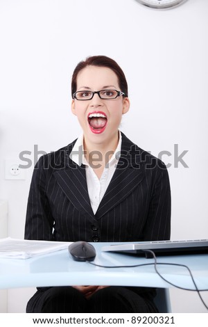 Pretty caucasian screaming businesswoman sitting behind the desk in the office.