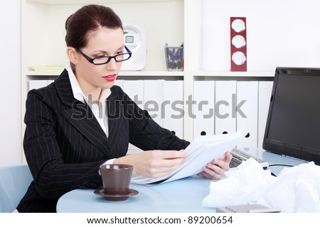 Pretty caucasian businesswoman reading files near crumpled files behind the desk in the office.