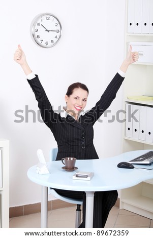Pretty caucasian businesswoman with hands in the air gesturing okay sign and sitting behind the desk in the office.