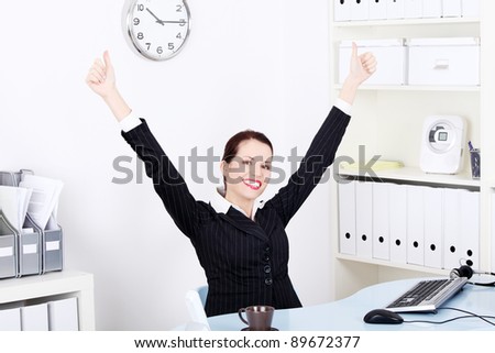 Pretty caucasian businesswoman with hands in the air gesturing okay sign and sitting behind the desk in the office.