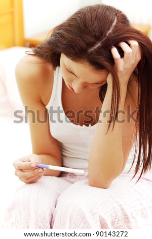 closeup of a beautiful young woman in the bedroom worrying because of the pregnancy test result.