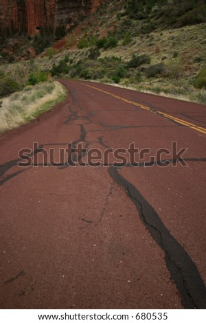 old red patched up road leading to mountain
