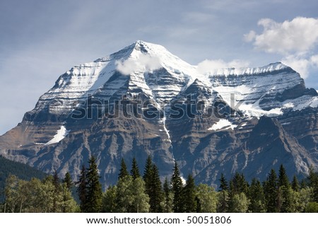 Sunlit trees in front of snow covered Mount Robson near Jasper, Canada