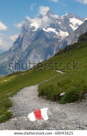 This mountain trail - the Eiger trail in the Swiss Alps - is clearly marked with a white and red stone. In the back the Wetterhorn above Grindelwald.