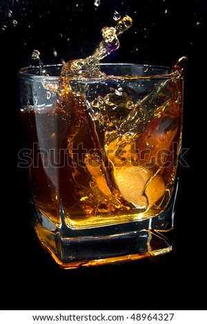 Whiskey splash. Glass on black background.