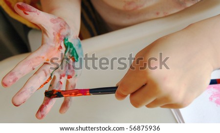 A child holds a brush and paints hand paint