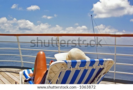 A woman sits on the upper deck of a cruise ship and overlooks the ocean
