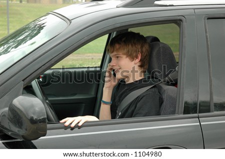 A teen driver sits on the side of the road in his parent's SUV and talks on his cell phone