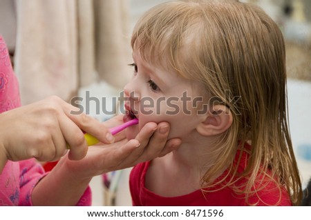 A mother brushes her daughter\'s teeth