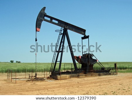 A grasshopper pump pumps oil in the midst of a wheat field