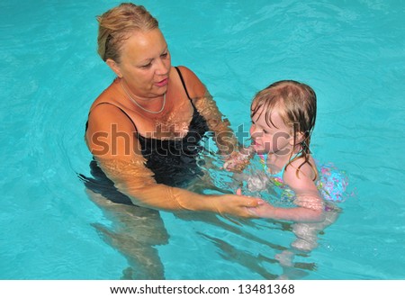 A grandmother and her granddaughter work on their swimming in the pool