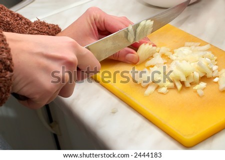 Food preparation-housewife makes a dinner on kitchen and cuts an onions on small slices