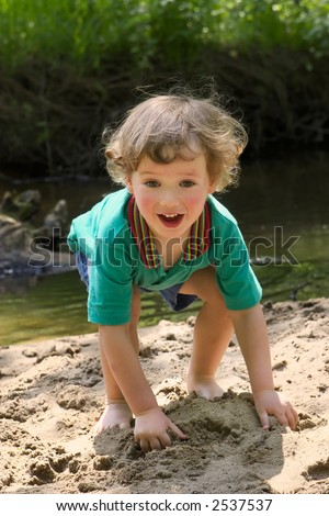 Child plays with water in small river at hot summer day
