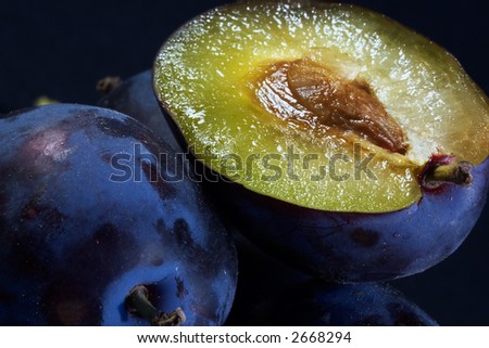 Dark blue ripe fleshy plums-one from them is cut half and expires with sweet juice