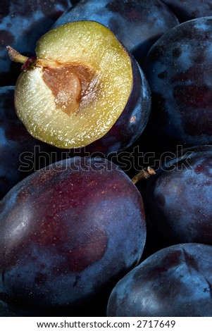 Dark blue ripe fleshy plums-one from them is cut half and expires with sweet juice