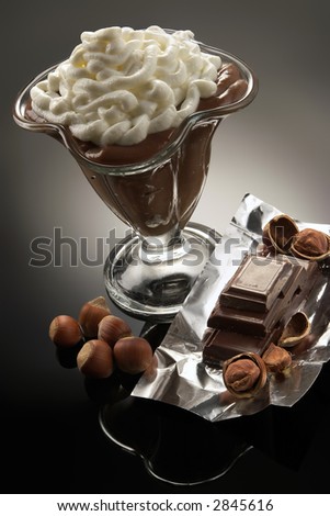 Coffee dessert with whipped cream on a background of chocolate and nuts-high-calorie delicacy