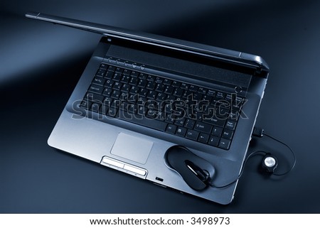 Black laptop and black mouse on a black background