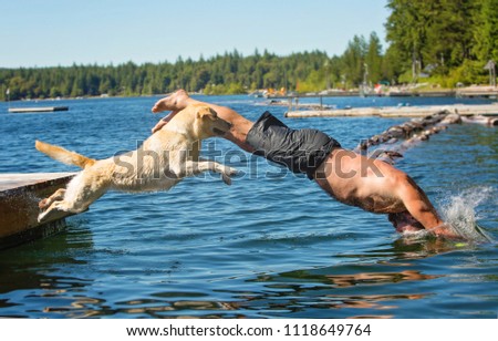 Man and Yellow lab dog jump into lake off dock together