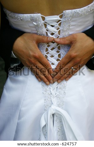 stock photo hands in the shape of a heart with wedding band on grooms hand