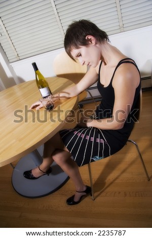 woman sitting with bowed head and wine bottle