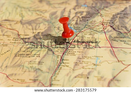 Albuquerque marked on map with red pushpin. Selective focus on the word Albuquerque and the bottom of pushpin. Pin is in an angle and casts shadow to the left.