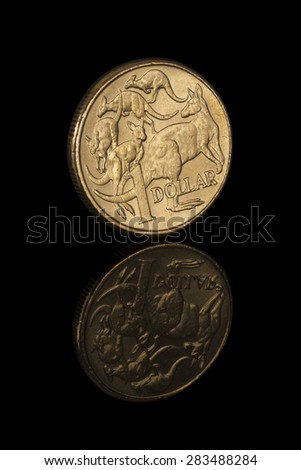 Australian one dollar coin with reflection of the whole coin. Low key image with black background. Tail side of the coin featured in an angle with kangaroos and 1 dollar written on it. Vertical image.